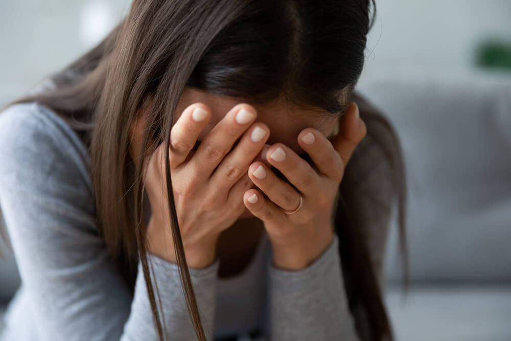 Close up of a grieving woman hiding her face in her hands